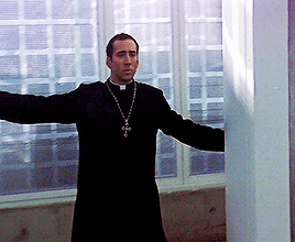 A Priest With His Arms Outstretched And A Cross On His Neck GIF