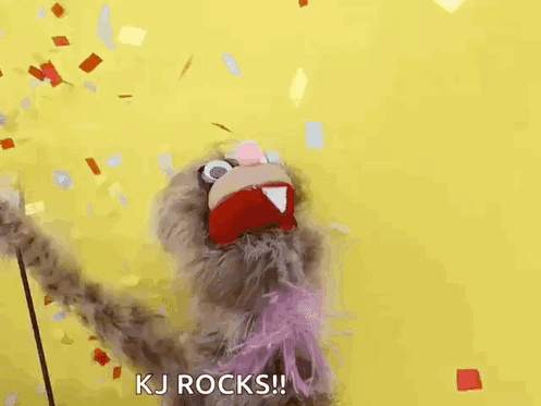 A Puppet Is Standing In Front Of A Yellow Background And Confetti Is Falling Around It . GIF