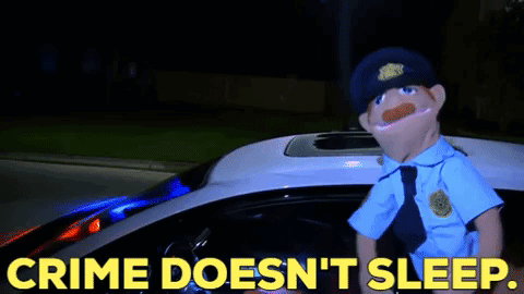 A Puppet Police Officer Is Standing In Front Of A Police Car With The Words Crime Does N't Sleep GIF