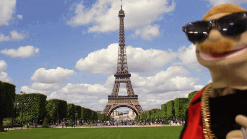 A Puppet Stands In Front Of The Eiffel Tower In Paris GIF