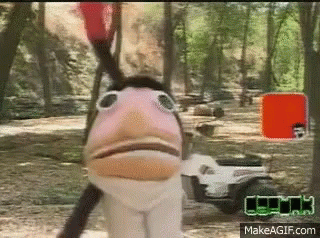 A Puppet With A Bird 'S Head Is Standing Next To A Golf Cart In A Forest . GIF