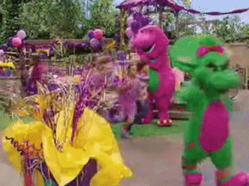 A Purple And Green Dinosaur Standing Next To A Yellow Flower GIF