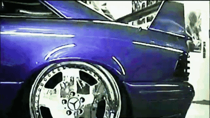 A Purple Car With Chrome Wheels And A Mercedes Logo On The Front GIF
