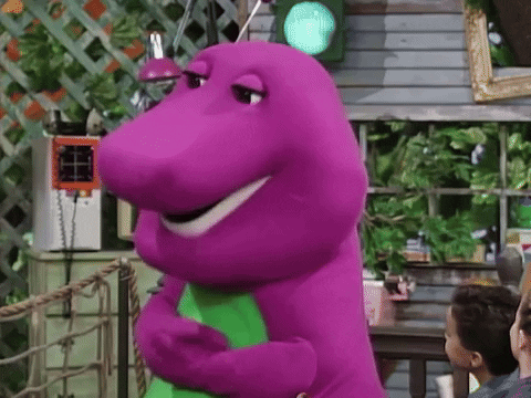 A Purple Dinosaur Is Standing In Front Of A Green Light And Smiling . GIF