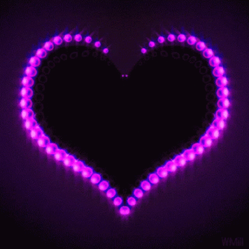 A Purple Heart Is Surrounded By Purple Lights On A Dark Background GIF