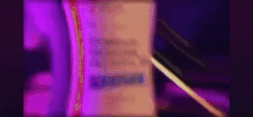 A Purple Light Is Shining On A Book With A Pen . GIF