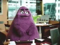 A Purple Monster Is Sitting At A Desk In An Office GIF