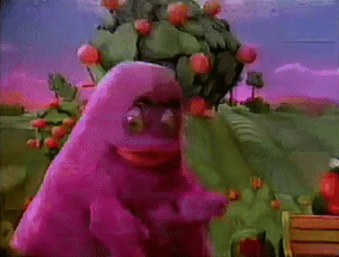 A Purple Monster Is Standing In Front Of A Cactus Tree . GIF