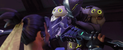 A Purple Robot With Yellow Eyes Is Being Held By Two People GIF