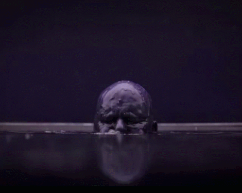 A Purple Skull Is Floating In A Dark Room In The Water . GIF