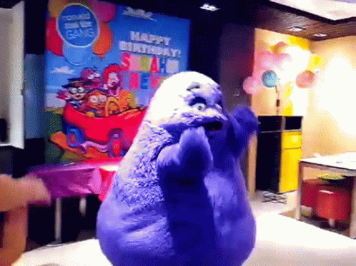 A Purple Stuffed Animal Is Dancing In Front Of A Sign That Says Happy Birthday Mcdonald 'S GIF