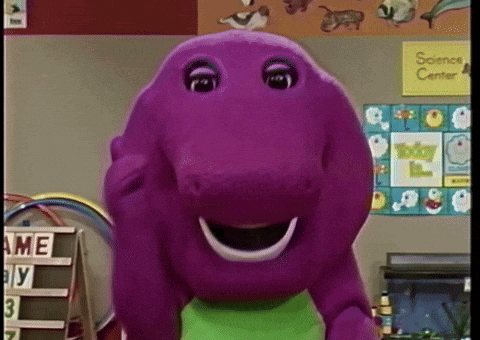 A Purple Stuffed Animal Is Smiling In Front Of A Science Center Sign GIF