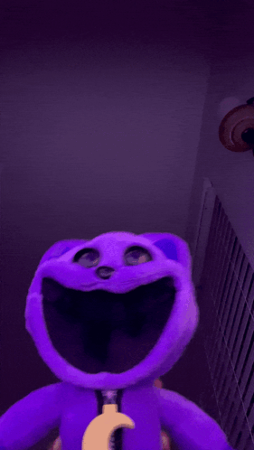 A Purple Stuffed Animal With Its Tongue Sticking Out GIF
