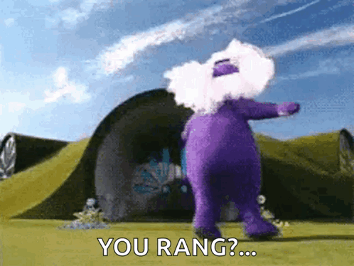 A Purple Teddy Bear Is Standing In Front Of A Building And Says You Rang ? GIF