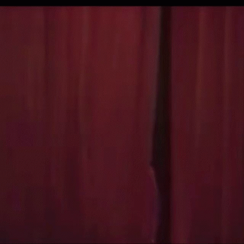 A Purple Teddy Bear Is Standing In Front Of A Pink Curtain With Hearts Coming Out Of It . GIF