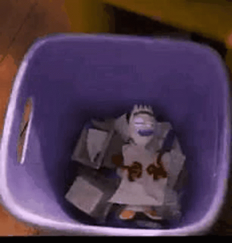 a purple trash can filled with a stuffed animal and papers .