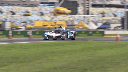 A Race Car Is Driving Down A Track With A Yellow Banner That Says Rolex On It GIF