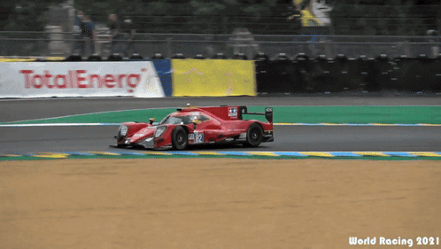 A Race Car Is Driving On A Track With A Total Energy Banner Behind It GIF