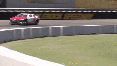 A Race Car Is Going Around A Curve On A Track With A Sign That Says Rock Speedway In The Background GIF