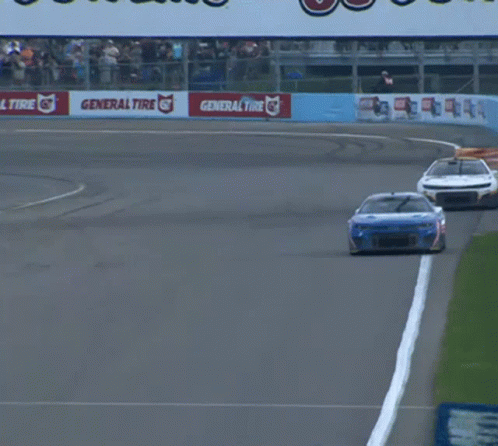 A Race Car Is Going Down A Track With A Go Bowling Sign In The Background GIF