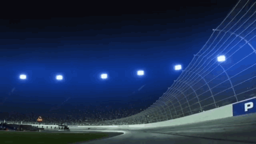A Race Track Is Lit Up At Night With A Lot Of Lights On It . GIF