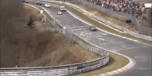 A Race Track With Cars On It And A Crowd In The Background GIF