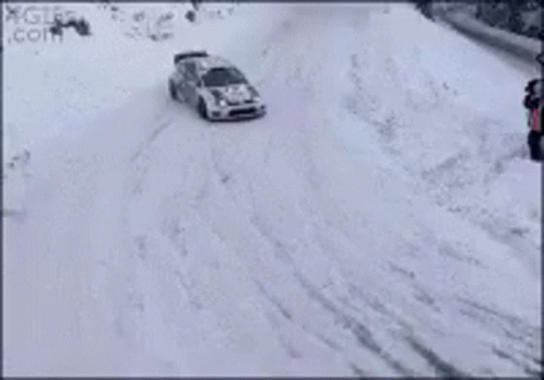A Rally Car Is Driving Through The Snow On A Track . GIF