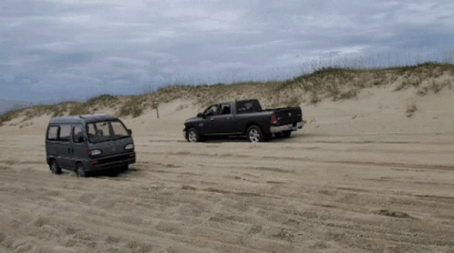A Ram Truck And A Van Are Parked On A Sandy Beach GIF
