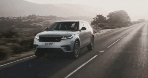 A Range Rover Is Driving Down The Road GIF