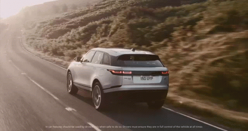A Range Rover Velar Is Driving Down A Road GIF
