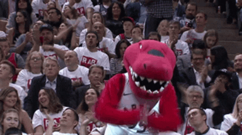 A Raptors Mascot Stands In Front Of A Crowd Of People Wearing Raptors Shirts GIF