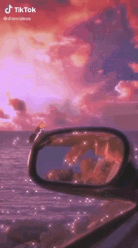 A Rear View Mirror Of A Car With A Sunset In The Background . GIF