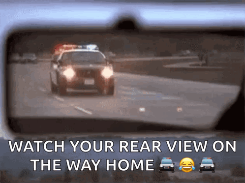 A Rear View Mirror Shows A Police Car Driving Down A Road GIF