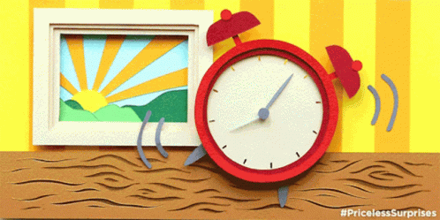 A Red Alarm Clock Sits On A Wooden Table Next To A Picture GIF