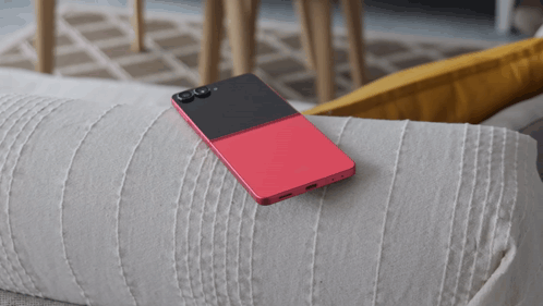 A Red And Black Cell Phone Is Laying On A White Couch GIF