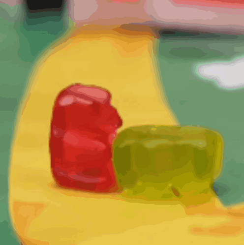 A Red And Green Gummy Bear Sit On A Yellow Surface GIF
