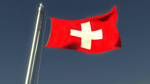 A Red And White Flag With A White Cross On It Is Flying In The Wind GIF