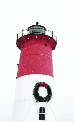 A Red And White Lighthouse With A Wreath On Top GIF