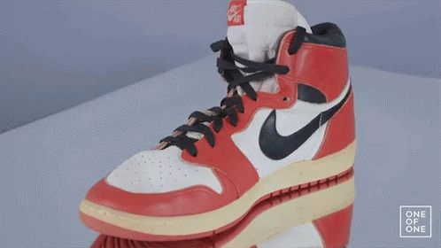 A Red And White Nike Shoe Is On A White Surface GIF
