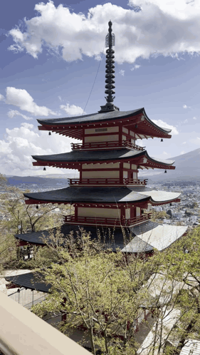 A Red And White Pagoda With A Clock On Top GIF