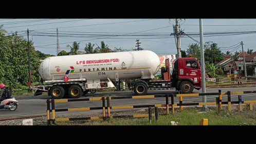 A Red And White Pertamina Truck Is Driving Down A Road GIF