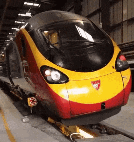 A Red And Yellow Train With A Shield On The Front GIF