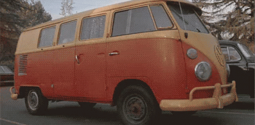 A Red And Yellow Van Is Parked On A Street GIF
