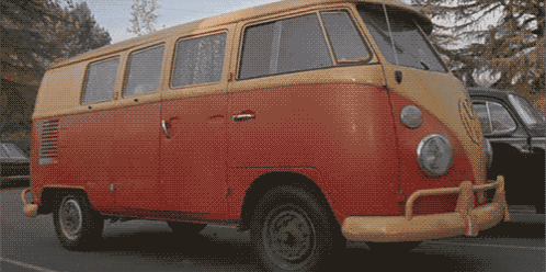 A Red And Yellow Van Is Parked On A Street GIF