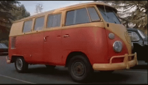 A Red And Yellow Van Is Parked On The Side Of A Road . GIF