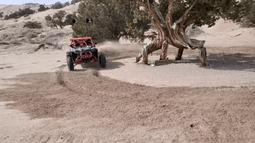 A Red Atv Is Driving Down A Dirt Road GIF