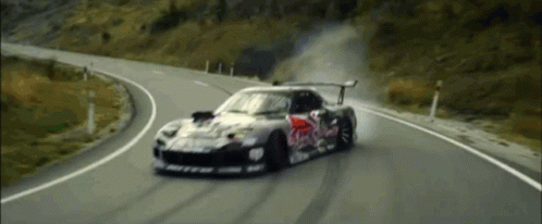 A Red Bull Race Car Is Driving Down A Curvy Road GIF