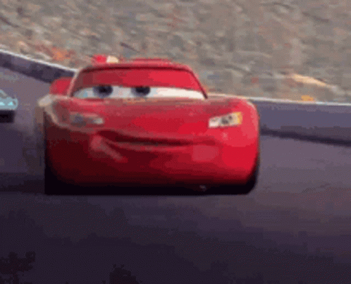 A Red Car From The Movie Cars Is Driving Down A Track . GIF