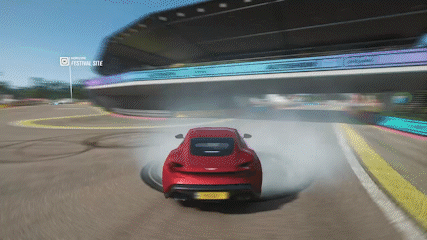 A Red Car Is Drifting On A Race Track With A Festival Site Displayed In The Background GIF