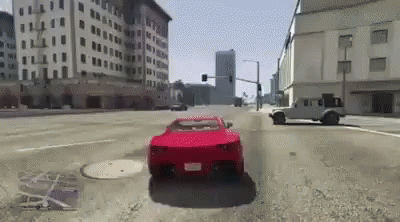 A Red Car Is Driving Down A City Street With Buildings In The Background . GIF